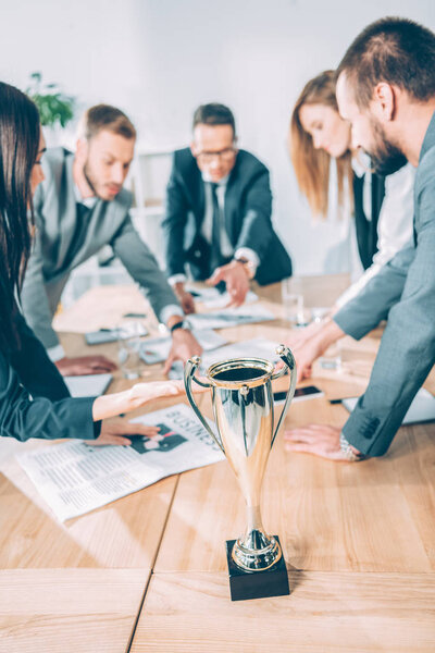 businesspeople having conversation in conference hall with champion cup on table