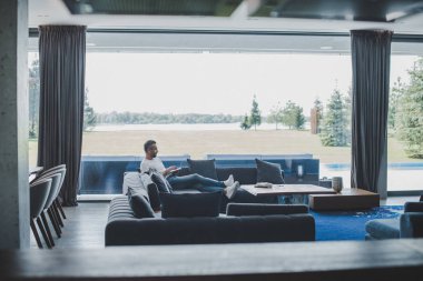 Erkek Freelancer laptop ile evde kanepenin üzerinde çalışan uzak görünümü 