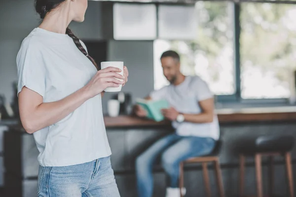 Sebagian Pandangan Wanita Memegang Cangkir Kopi Sementara Pacarnya Membaca Buku — Foto Stok Gratis