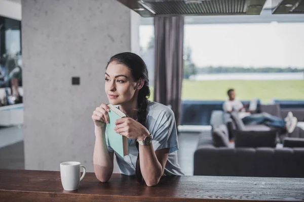 Thoughtful Woman Book Looking Away Tabletop Coffee Cup While Her — Free Stock Photo