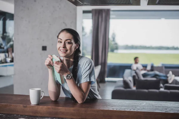 Donna Felice Con Libro Guardando Fotocamera Tavolo Con Tazza Caffè — Foto stock gratuita