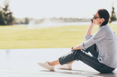 seçici odak içinde güneş gözlüğü smartphone açık havada üzerinde konuşmak mutlu kadın 