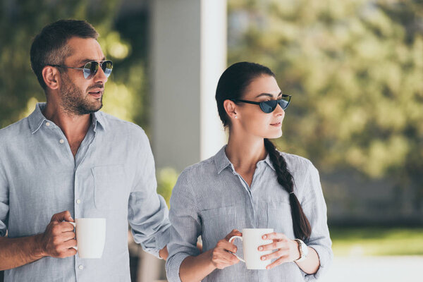 selective focus of couple in sunglasses with coffee cups outdoors