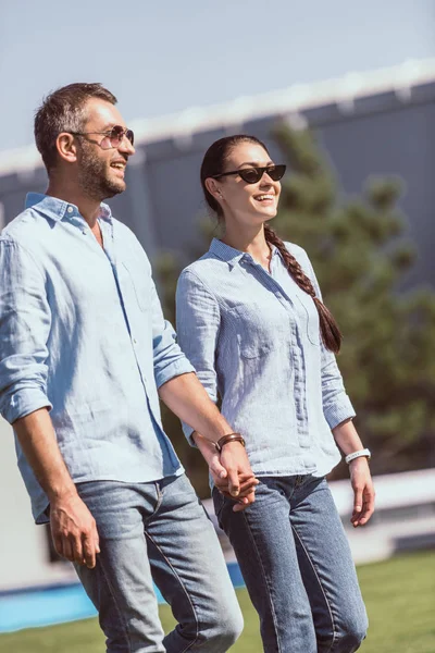 Happy Couple Sunglasses Holding Hands Walking Outdoors — Free Stock Photo