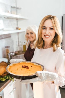 kıdemli anne ve mutlu yetişkin kızı birlikte evde kabak pasta pişirme
