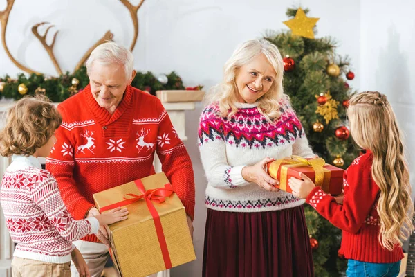 happy grandparents and giving gift boxes for kids on christmas