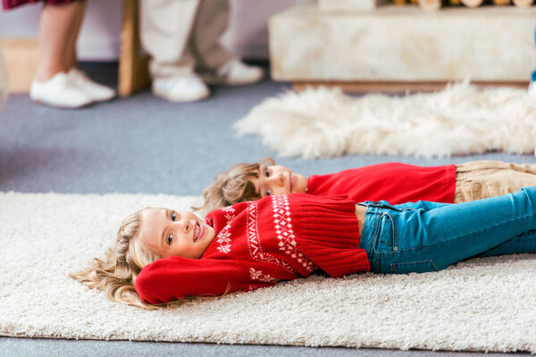 siblingsadorable siblings in red sweaters lying on floor