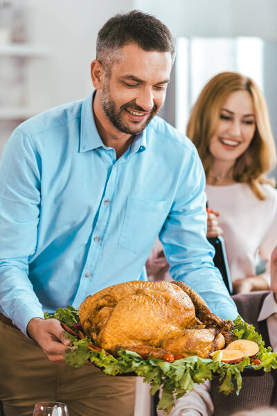 happy young man serving turkey on thanksgiving table