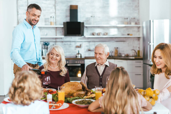 happy family having delicious thanksgiving dinner together at home while father pouring wine