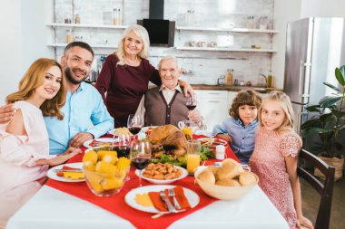 big family having delicious thanksgiving dinner together at home and looking at camera clipart