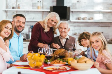 big family having thanksgiving dinner together at home and looking at camera clipart