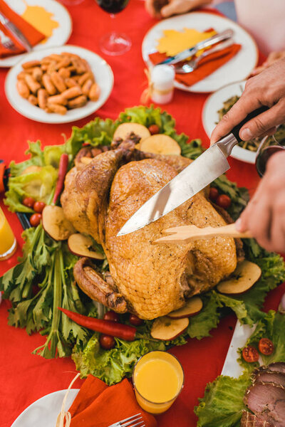 cropped shot of man cutting turkey on thanksgiving table