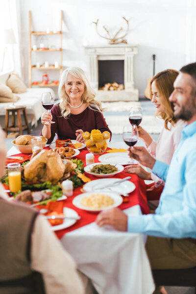 senior happy woman looking at camera during thanksgiving dinner with family