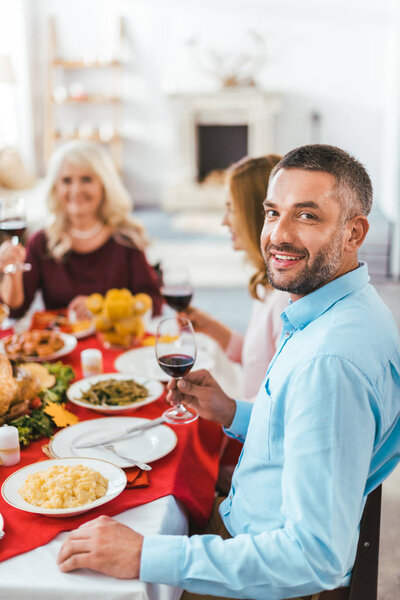 handsome young man looking at camera during thanksgiving dinner with family