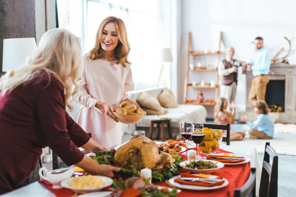 happy young and senior women serving thanksgiving day table