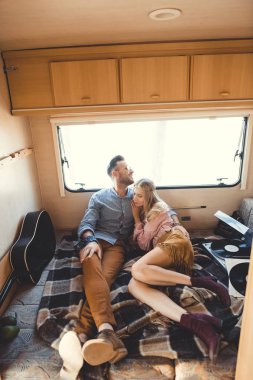 güzel çift sarılma ve akustik gitar ve vinil kayıtlar ile kamp aracına içinde dinlenme