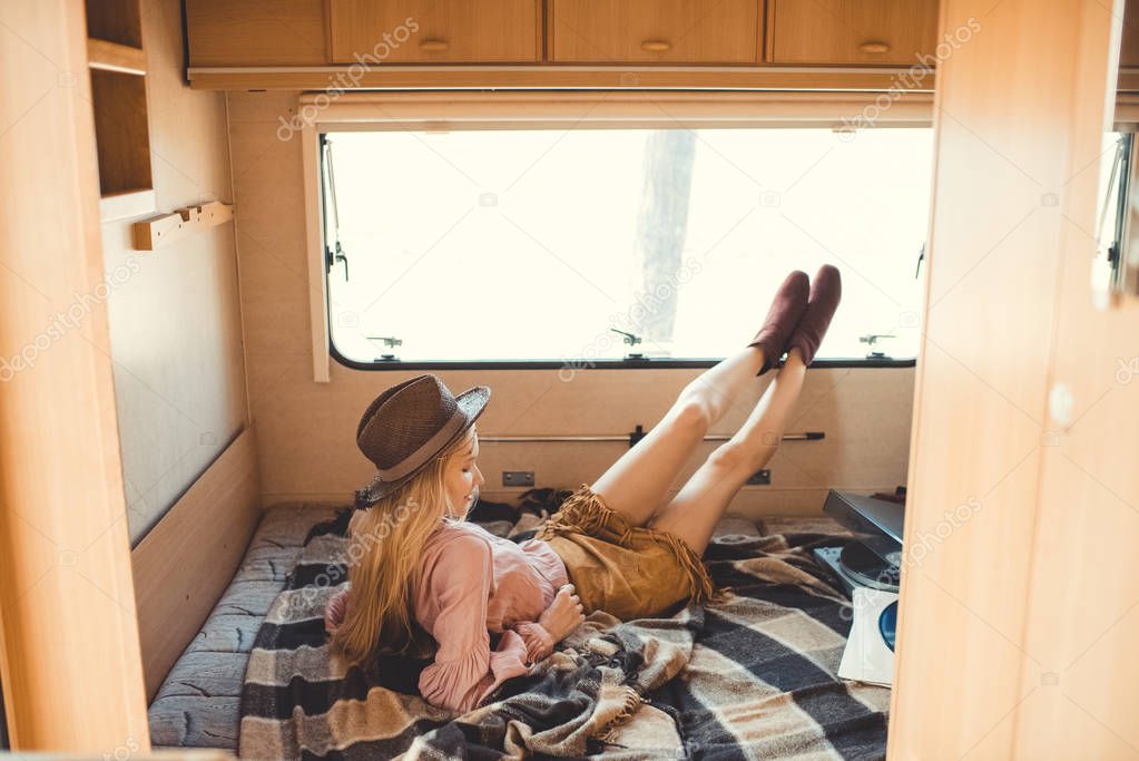 hippie girl in hat resting inside camper van with vinyl player and records