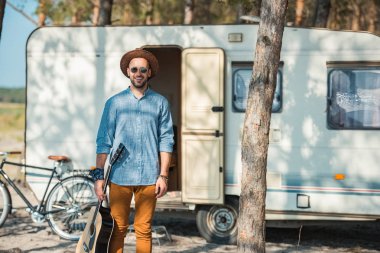 gitar tutarak ve treyler Bisiklet ile ayakta mutlu adam