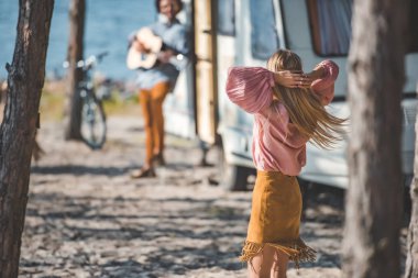 sarışın hippi kız erkek kamp aracına yakınındaki gitar çalmak süre dans