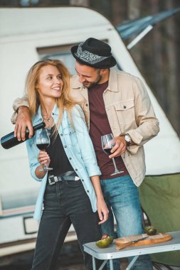 yakışıklı adam kamp aracına yakın mutlu kız için şarap dökme