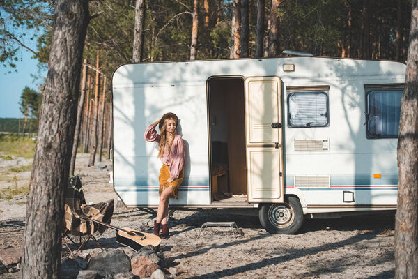 beautiful hippie girl posing near camper van in forest