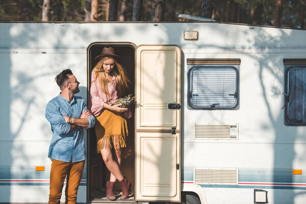 young hippie couple with pineapple posing near trailer in camp
