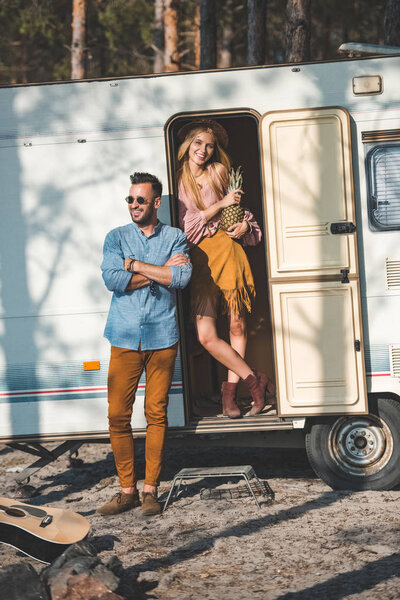 beautiful hippie couple with pineapple posing near campervan