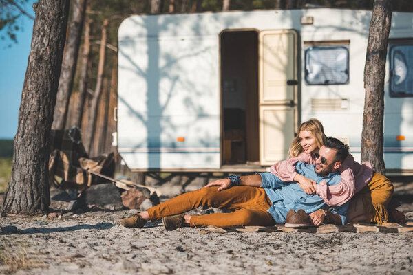 hippie young couple relaxing on blanket near camper van