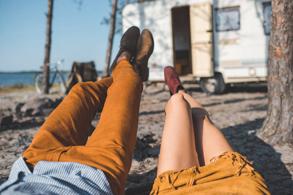 partial view of couple relaxing near camp trailer in nature