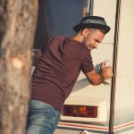 Вид сзади красивого человека, толкающего прицеп Вид сзади красивого человека, толкающего прицеп