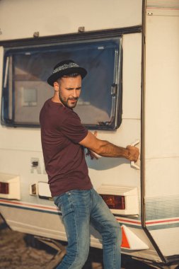 handsome man trying to open door of campervan clipart