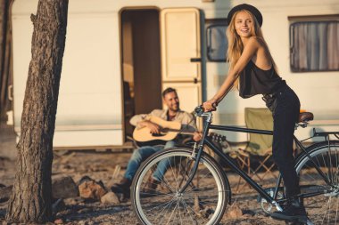 seçici odak bir bisiklet ve römork yakınındaki gitar çalmak adam mutlu kız
