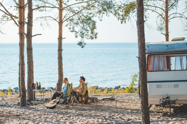 young couple having picnic at campervan near the sea
