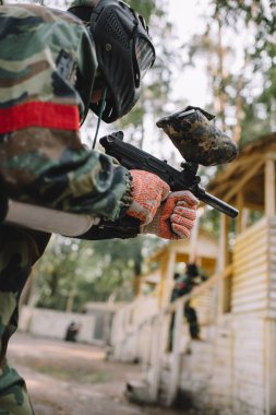 gözlüğü maskesi ve açık havada paintball silahı tarafından hedefleyen kamuflaj erkek paintball oyuncu düşük açılı görünümü 