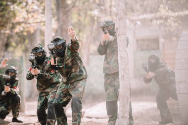 kamuflaj üniforma el ile onun takım açık havada işaretleri silahlı işaret içinde paintball oyuncu 