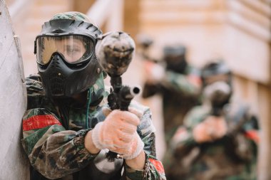 Açık havada marker silah tarafından hedefleyen paintball sıçrama kapsadığı gözlüğü maskesinde erkek paintballer 