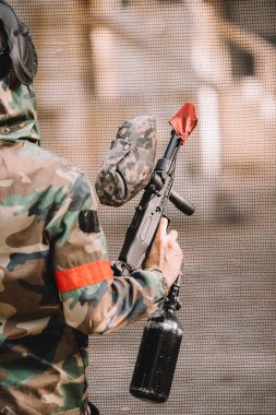 kısmi gözlüğü maskesi ve kamuflaj paintball silahı açık havada tutan erkek paintball oyuncu görünümünü 