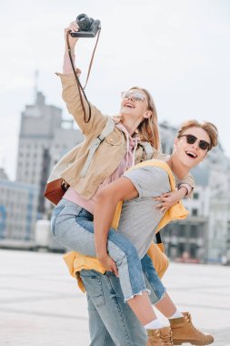 neşeli erkek kız o alarak fotoğraf makinesinde iken piggybacking