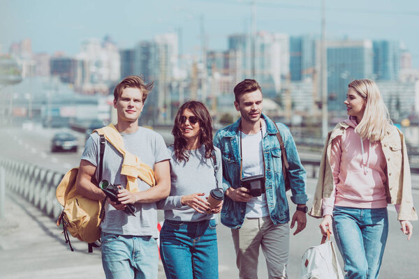 young friends with map and backpacks traveling together in new city