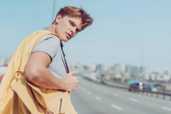 若い男が道でヒッチハイクの背面図 — ストック写真