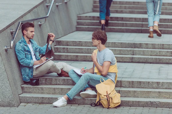 Young Men Notebooks Sitting City Steps New City — Free Stock Photo