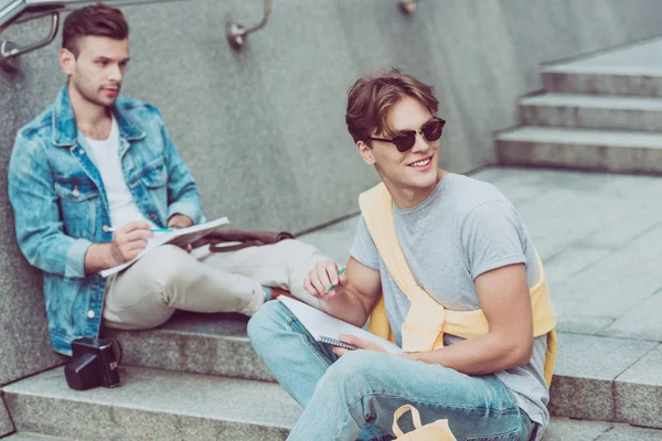 Young Men Notebooks Sitting City Steps New City — Free Stock Photo