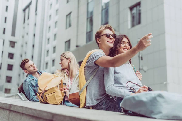 Jovens Casais Turistas Sentados Cidade Enquanto Homem Feliz Mostrando Algo — Fotografia de Stock