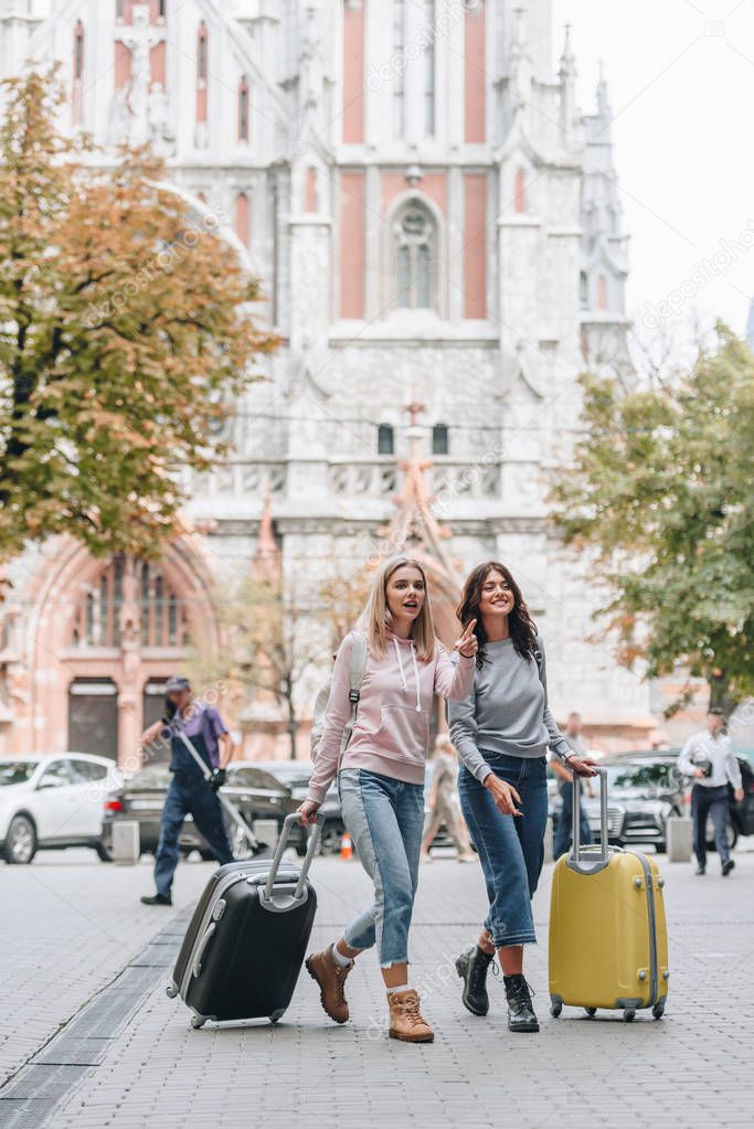 female tourists with backpacks and baggage walking on city street