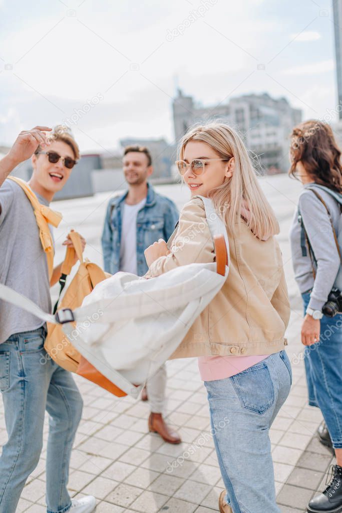 young stylish friends walking in city 