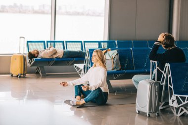 Genç kadın Havaalanı terminal bekleyen uçuş sırasında lotus pozisyonda meditasyon