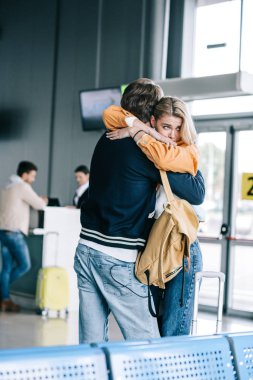 emotional young couple hugging in airport terminal  clipart