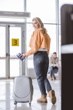 geçişi ve bavul Havaalanı kameraya gülümseyen yatılı pasaport, çekici genç kadın 