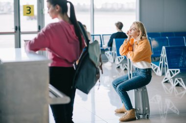 Bavul Havaalanı terminal üzerinde oturan sıkılmış genç kadın