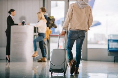 cropped shot of man with suitcase going to check-in desk in airport clipart